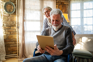 Senior couple having fun and laughing while using their tablet pc computer.