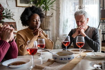 Multiethnic family praying at the table worshipping the Lord