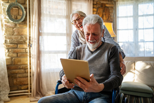 Senior couple having fun and laughing while using their tablet pc computer. - Powered by Adobe
