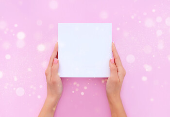 Obraz premium blank sheet of paper in female hands on a light pink background 