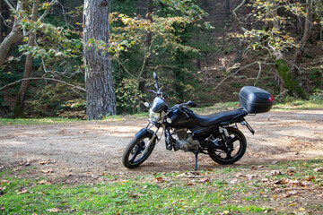 Motorcycle alone on the road. Touring in the forest. Motorcycle on the forest road.  Motorcycle in nature parking on a path.