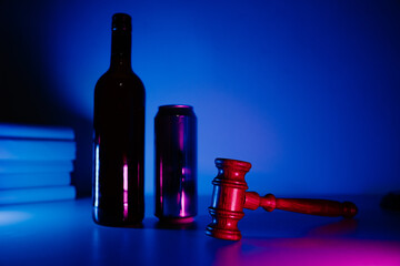 Bottle with whisky, jar of beer and judge gavel in neon light, alcohol and crimes concept