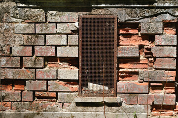 Old Rusty Iron Grill over Window in Derelict Brick Building 