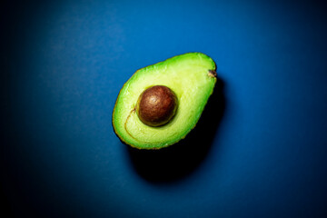 half avocado with core on blue background