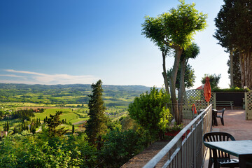 Stunning view of yellow fields and farmlands with small villages on the horizon. Rural landscape of rolling hills, curved roads and cypresses of Tuscany, Italy.