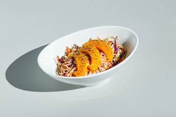 Cole slow salad with mango and poppy seeds on light background. Hard light, deep shadow