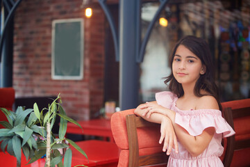 A school-age girl in a pink dress on the streets of the city.