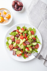 Salad with lettuce, cucumbers, tomatoes, olives and avocados in white plate on the table