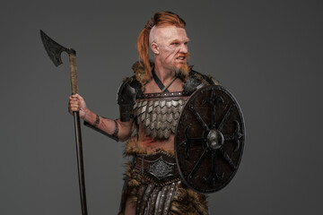 Barbaric viking warrior wielding axe and shield isolated on gray