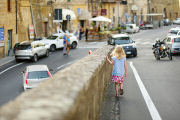 Young girl exploring the famous Pitigliano town, located atop a volcanic tufa ridge. Beautiful italian towns and villages. Etruscan heritage, Grosseto, Tuscany, Italy.