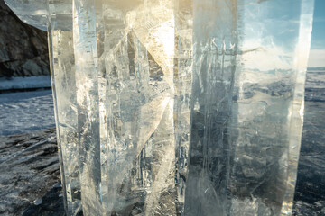 Transparent block of ice with cracks in the rays of the sun at sunset. Winter natural abstraction of Baikal ice