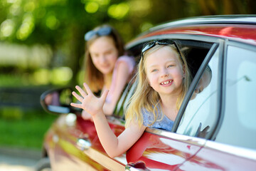 Funny young girls sticking their heads out the car window looking forward for a roadtrip or travel.
