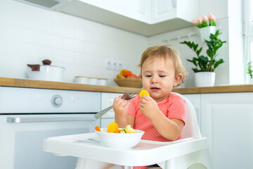 The baby eats vegetables on a chair. Selective focus.