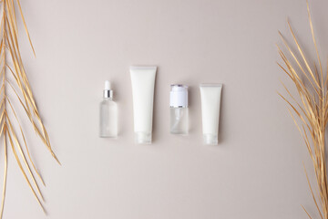Cosmetic skin care products with palm leaf  on grey background. Flat lay, copy space