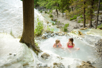 Young girls bathing in Bagni San Filippo, small hot spring containing calcium carbonate deposits,...