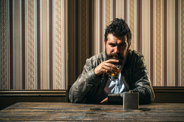 Fototapeta premium Degustation tasting expensive whiskey. Bearded man with glass of whiskey. Male model drinking brandy or cognac. Expensive drink.