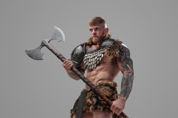 Handsome northern warrior holding axe against gray background