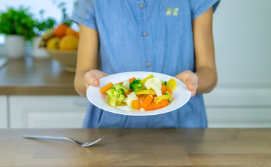 The child eats vegetables on a chair. Selective focus.