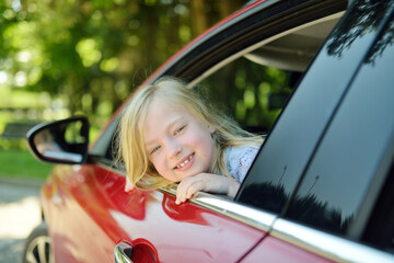Funny young girl sticking her head out the car window looking forward for a roadtrip or travel.