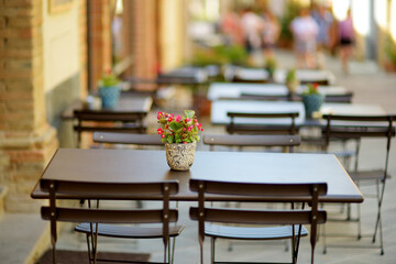 Empty restaurant table in medieval street of Montalcino town, located on top of a hill top and surrounded by vineyards, known worldwide for the production of wine. Tuscany, Italy.