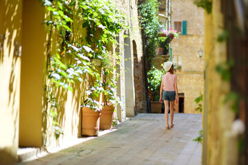 Plakat Young girl exploring in Pienza, a village located in the beautiful Tuscany valley, known as the 'ideal city of the Renaissance' and a 'capital' of pecorino cheese.