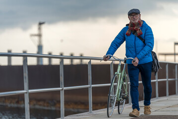 Portrait senior man walking with his bicycle next to the sea