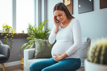 Obraz premium A frustrated young woman who suffers from a headache while at home with the expression that she is not well, with her eyes closed. The concept of pregnancy and pain