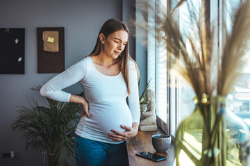 Pregnant woman feels stomach pain, tries to relax by the window, suffers from abdominal pain, pregnant woman has cramps, copy space