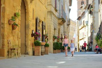 Naklejka premium Young sisters exploring in Pienza, a village located in the beautiful Tuscany valley, known as the 'ideal city of the Renaissance' and a 'capital' of pecorino cheese.