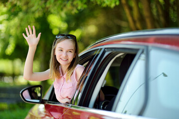 Funny young girl sticking her head out the car window looking forward for a roadtrip or travel.