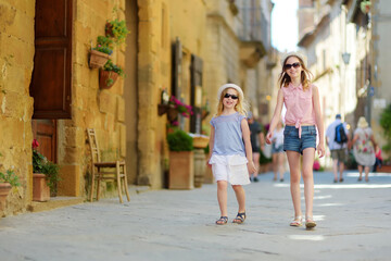 Fototapeta na wymiar Young sisters exploring in Pienza, a village located in the beautiful Tuscany valley, known as the 'ideal city of the Renaissance' and a 'capital' of pecorino cheese.