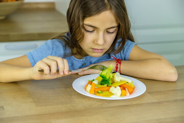 The child eats vegetables on a chair. Selective focus.