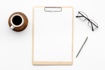 White office desk table with empty paper on clipboard