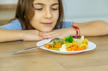 Obraz na płótnie Canvas The child eats vegetables on a chair. Selective focus.