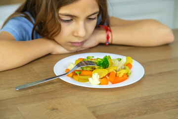The child eats vegetables on a chair. Selective focus.