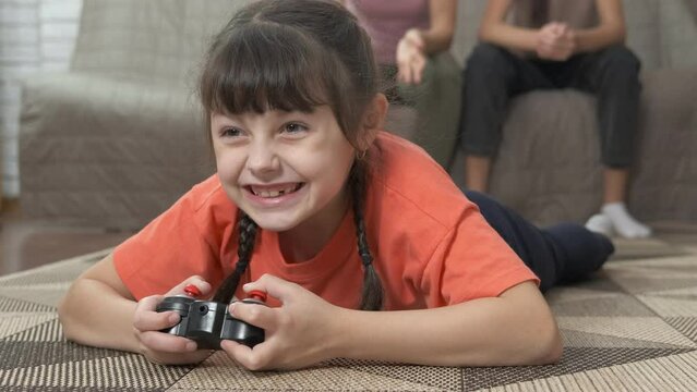 Weekend with video game. A family pas their weekend with video game in the room. Cute little girl with a joystick plays games.