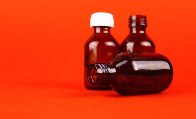 Three glass bottles for medication on an orange background