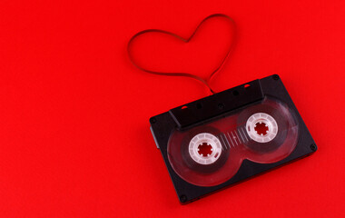 Black audio cassette on a red background with a film heart. Saint Valentine's Day. Symbol of love...