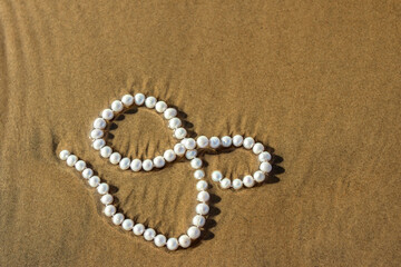 Fototapeta na wymiar Pearl beads lie on the sand in the water of the bay
