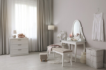 Wooden dressing table with decorative elements and makeup products in room. Interior design
