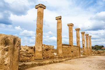 Ruins of an ancient temple in Paphos. Remains of carved marble columns. A row of seven columns as a...