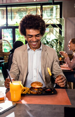 Fototapeta na wymiar Smiling African American businessman having lunch in restaurant.