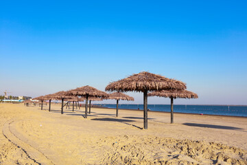 Umbrella from the sun with a roof of palm leaves on a background of the sea on a sunny day.