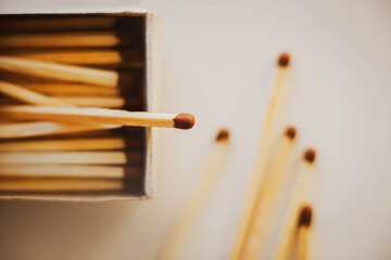 On a white table there is an open cardboard box with wooden matches, and next to it are five matches pulled out. Flammable items. Household items.