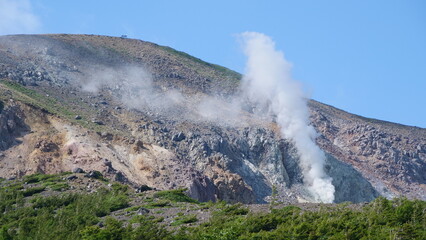 Fototapeta na wymiar 噴煙をあげる山。日本の風景。