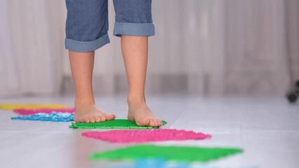 Little boy steps on orthopedic massage mats with different stiffness and texture. Feet Massage...