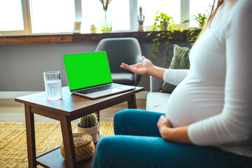 Cheerful mum sitting in chair in bright light flat and using pc laptop while speaking with intelligent doctor about pregnancy. Cropped view of pregnant patient having online consultation with doctor 