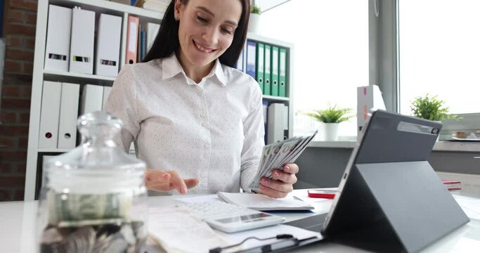 Happy woman counting cash on calculator in office closeup