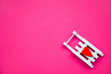 The concept of February 14. The postcard is festive. Valentine's Day. Valentine's day. White wooden sled on a pink background with a red heart. Free space for text
