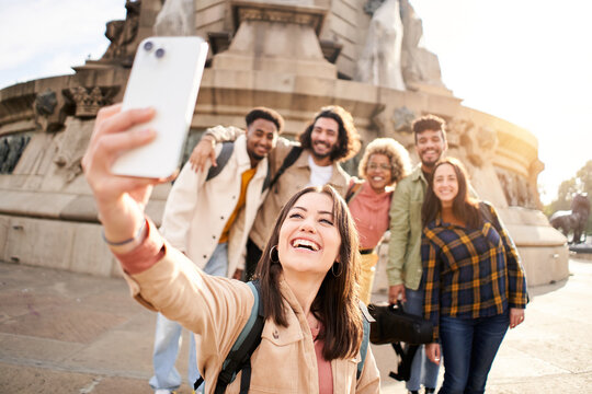Group of multi-ethnic young people taking a happy smiling selfie. Students having fun outdoors. Beautiful woman shoot a photo in smartphone with a friends.